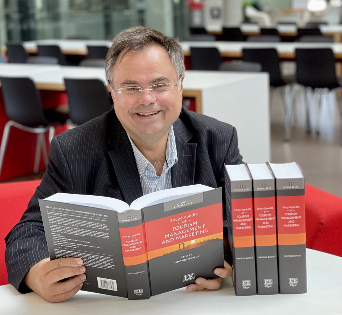 Professor Dimitrios Buhalis at XP Dorset 2025, pictured with the Encyclopedia of Tourism Management and Marketing.